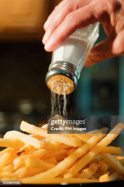 pouring salt on french fries - adicionar sal imagens e fotografias de stock