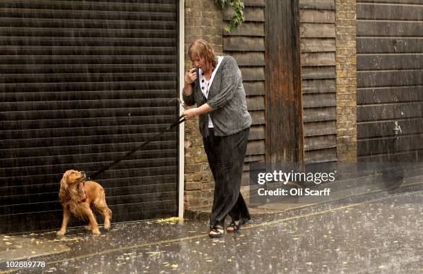 Heavy downpour of rain catches out a woman walking her dog in Westminster on July 14, 2010 in London, England. Rain showers will continue to affect...