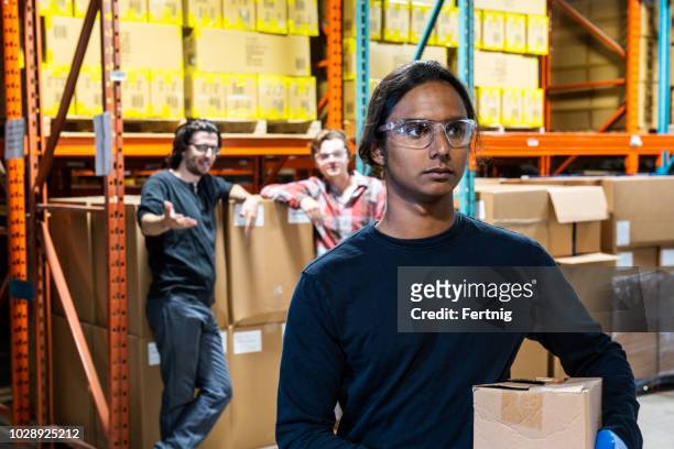 an industrial warehouse worker being the target of bullying - racism imagens e fotografias de stock