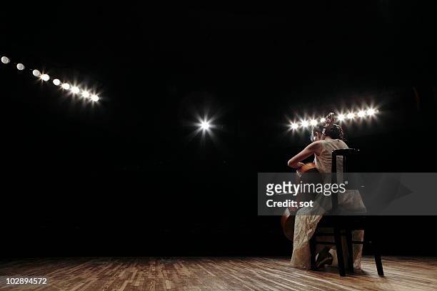a female cellist playing cello on stage, rear view - performing arts stage stock pictures, royalty-free photos & images
