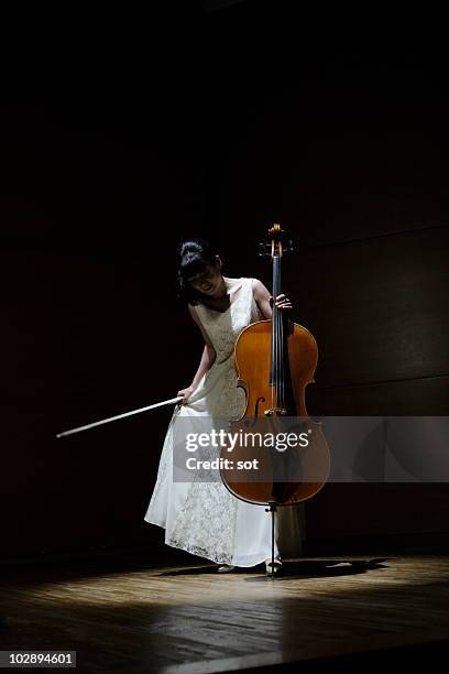 a female cellist making a bow on stage. - cellist stock pictures, royalty-free photos & images