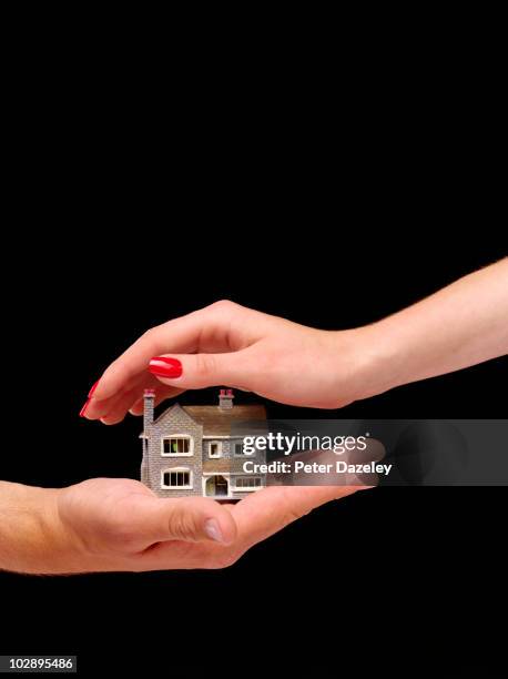 hands protecting house on black background - testament photos et images de collection