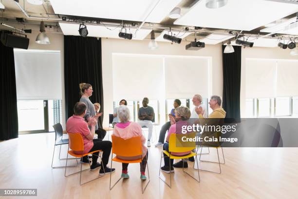 active seniors clapping for instructor in circle in community center - elderly cognitive stimulation therapy stockfoto's en -beelden