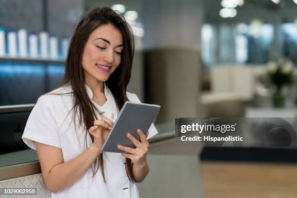 beautiful manager of a hair salon looking at the bookings on a tablet very happy - beautician stock pictures, royalty-free photos & images