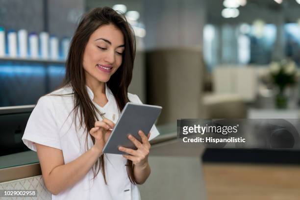 bela gerente de um salão de cabelo olhando as reservas em um tablet muito feliz - terapeuta de beleza - fotografias e filmes do acervo