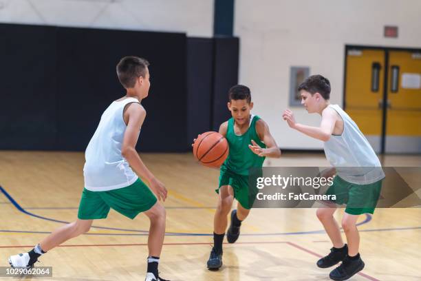élémentaires garçons jouant au basketball - stage sportif photos et images de collection