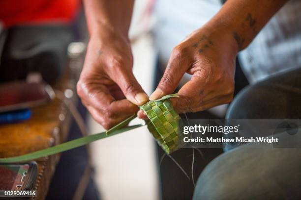 a woman learns the ancient craft of weaving bracelets from palm leaves at new zealand's lake aniwhenua. - maorí fotografías e imágenes de stock