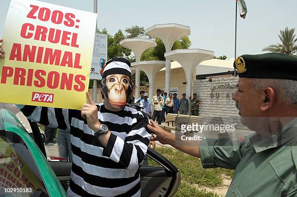An Emirati policeman talks to an activist of the People for the Ethical Treatment of Animals , wearing a prison suit and a monkey mask, outside the...