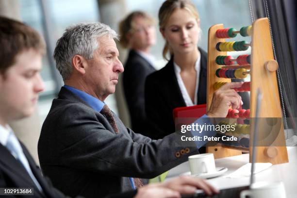 executives on laptops, older man with abacus - abaco fotografías e imágenes de stock