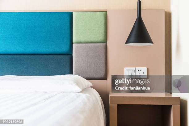 a lamp hanging over nightstand with plug socket in wall - nachttisch stock-fotos und bilder