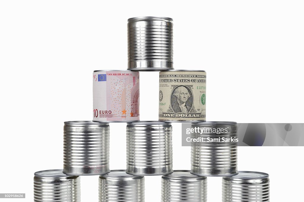 Cans pyramid surrounded by US dollar and Euro note