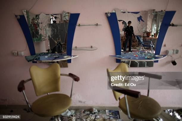 Kyrgyz police officer surveys the damage to a Kyrgyz owned hair salon that was reportedly looted and destroyed by Uzbek mobs during last weeks...