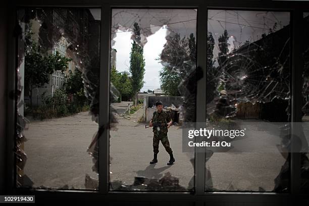 Kyrgyz police officer walks past a Kyrgyz owned hair salon that was reportedly looted and destroyed by Uzbek mobs during last weeks clashes in Osh,...