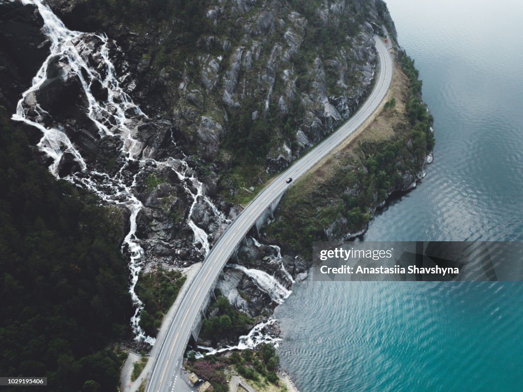 Luftaufnahme des riesigen Wasserfall fällt in den türkisblauen See und Straße in Norwegen