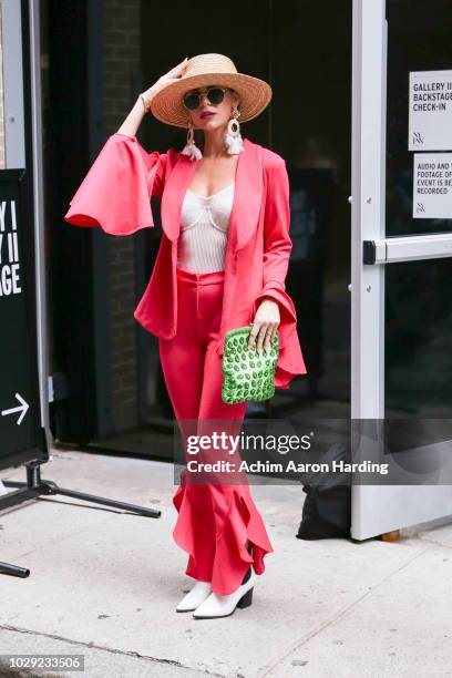 Julie Manganelli is seen wearing a fuschia pink Venus suit, green purse and white shoes on the street during New York Fashion Week on September 7,...