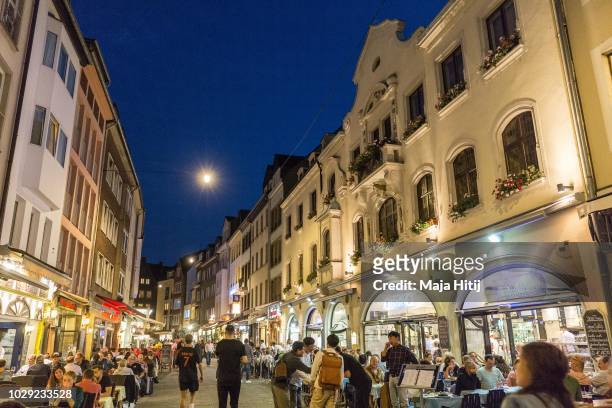 Visitors walk through Bolkerstrasse in "Altstadt" old city, on August 28, 2018 in Dusseldorf, Germany narrow streets in old town home to cocktail...
