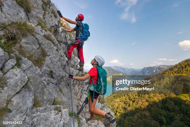 young girl with father is climbing to the top of a mountain in alps - rock climbing stock pictures, royalty-free photos & images