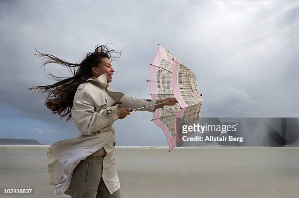 woman with umbrella on windy beach - stormy weather stock pictures, royalty-free photos & images