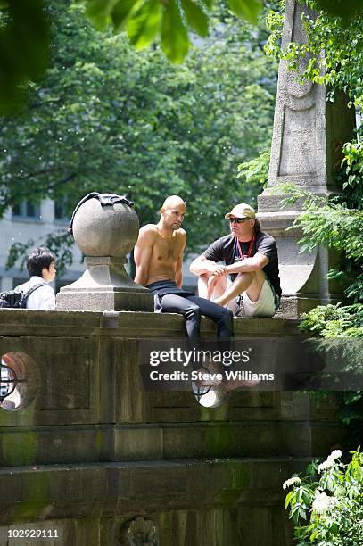 Surfer takes a break from surfing the Eisbach, a man made river using the Isar River as it's source of water which flows through the Englischer...