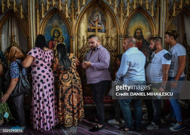 Romanians from the Roma community queue in front of Orthodox icons before going under a table in a local tradition to bring the fulfillment of their...