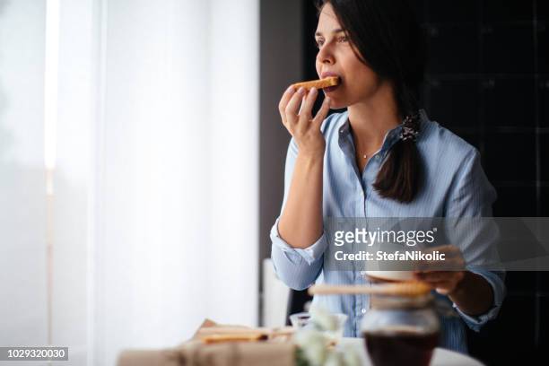 woman eating honey on toasted bread - woman eating toast stock pictures, royalty-free photos & images
