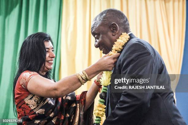 Sister of the late African National Congress anti apartheid local youth leader Lenny Naidu, Arusha Naidoo give a garland to South African President...