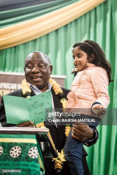 South African President Cyril Ramaphosa holds in his arms, Karusha Gounder, a 5 years old girl, as he reads the letter she wrote him during a meeting...