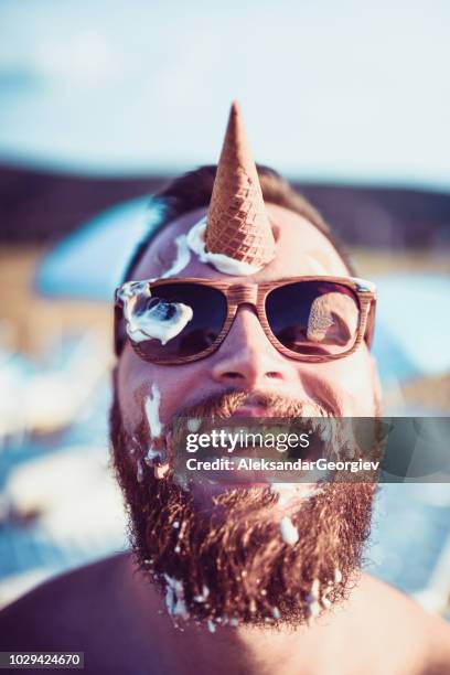 handsome bearded male playing with ice cream - bizarre humor stock pictures, royalty-free photos & images