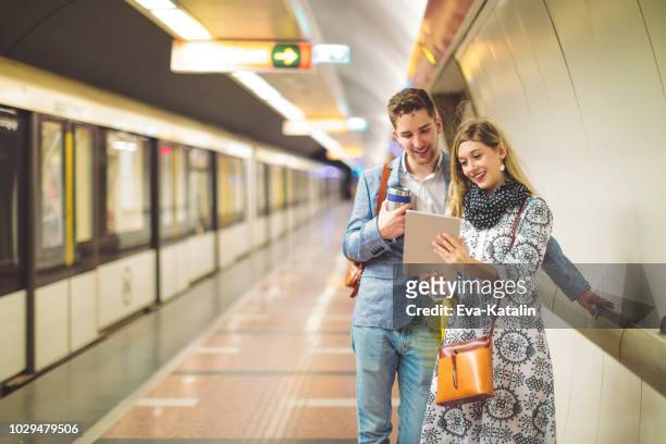 young couple is using mobile devices in the underground - budapest metro stock pictures, royalty-free photos & images
