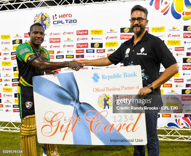 In this handout image provided by CPL T20, Rovman Powell of Jamaica Tallawahs receives the Republic Bank gift card from Richard Sammy during match 29...