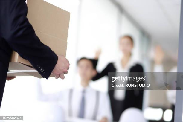 businessman carrying box of belongings,colleagues in background - rejet photos et images de collection