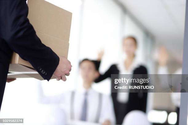 businessman carrying box of belongings,colleagues in background - afwijzing stockfoto's en -beelden
