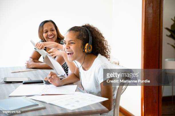 a mother and two daughters with homework open on the table in front of them - australian culture stock photos et images de collection