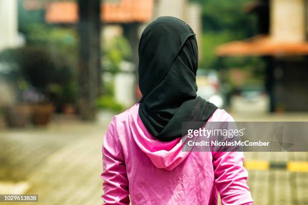 muslimische frau tragen hijab im wohngebiet hinten erschossen - schleier stock-fotos und bilder
