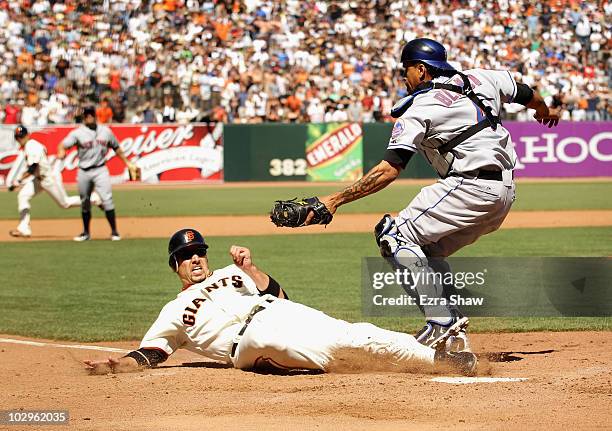 Travis Ishikawa of the San Francisco Giants slides in to home plate under the tag of New York Mets catcher Henry Blanco in the ninth inning AT&T Park...