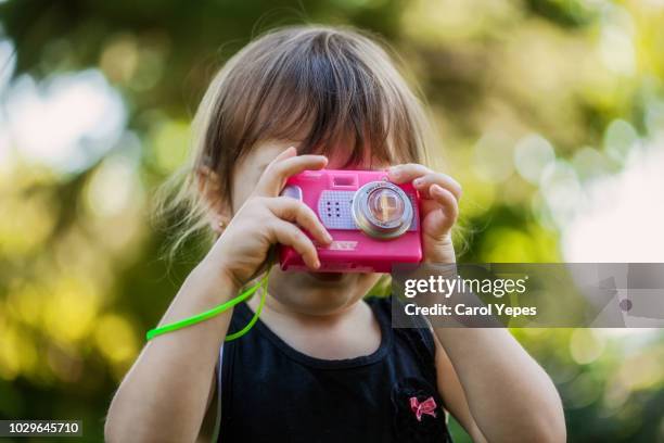 little girl taking pictures with toy camera outdoors - children camera stock pictures, royalty-free photos & images