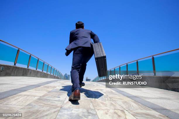 rear view of businessman running with briefcase - businessman running back stock pictures, royalty-free photos & images