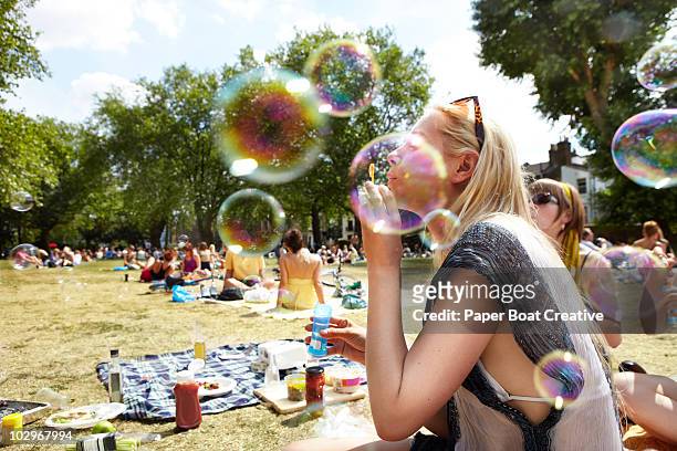 friends blowing bubbles in the park - picknick stockfoto's en -beelden