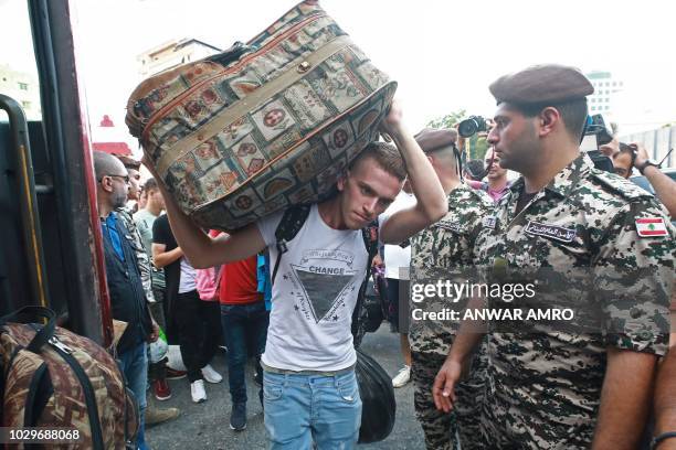 Syrian man carries a luggage as refugees prepare to leave the Lebanese capital Beirut to return to their homes in Syria on September 9, 2018. - A...