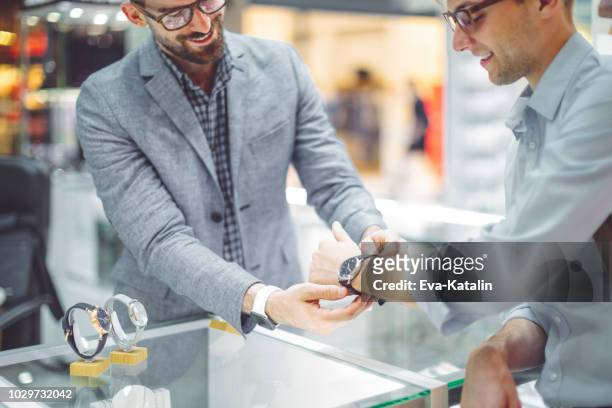 jongeman is winkelen voor een horloge - mens wrist watch stockfoto's en -beelden