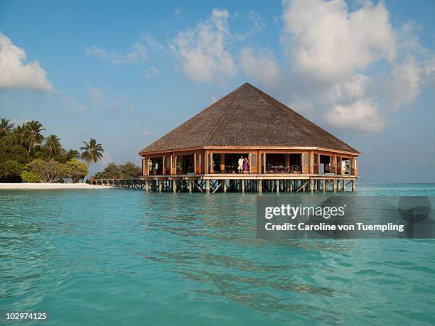 couple looking out from overwater restaurant - meeru island stock pictures, royalty-free photos & images