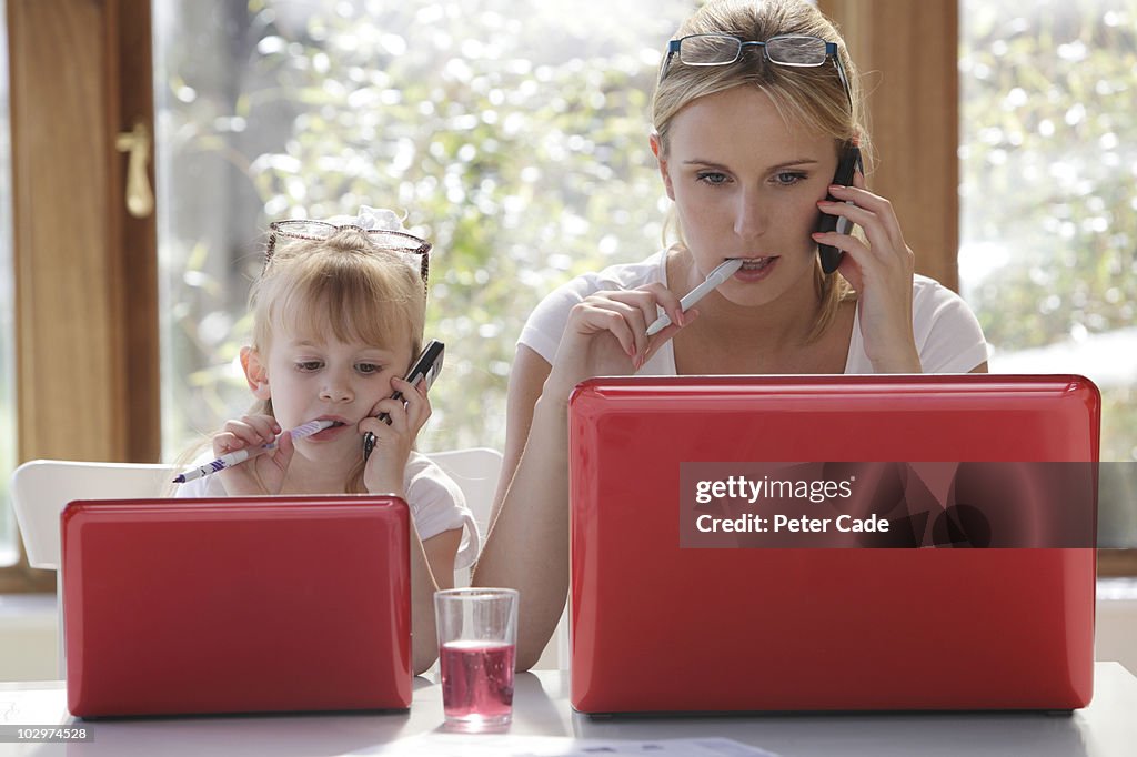 Daughter copy mother working on laptop
