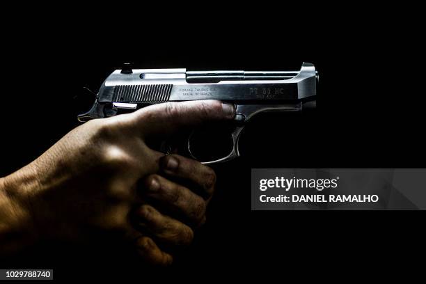 Man holds a gun at the 'Calibre 12' shooting club in Sao Goncalo, Rio de Janeiro, Brazil on September 03, 2018. The liberation of the use of firearms...