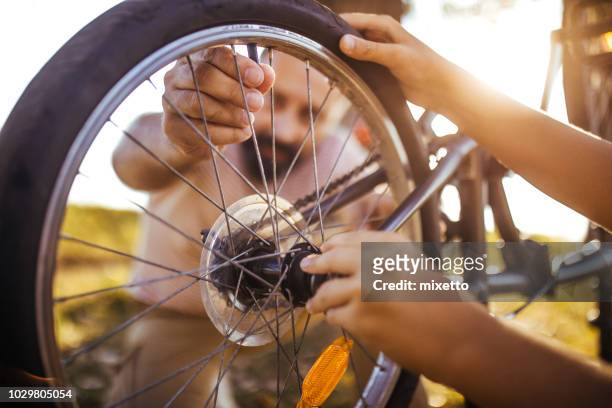 vater mit seinem sohn ein fahrrad-fixierung - fahrrad reparieren stock-fotos und bilder