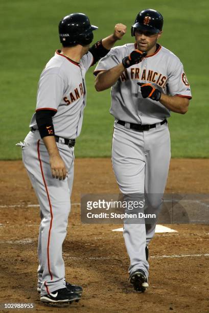 Nate Schierholtz of the San Francisco Giants is greeted by Travis Ishikawa after both score on Schierholtz' fourth inning home run against the Los...