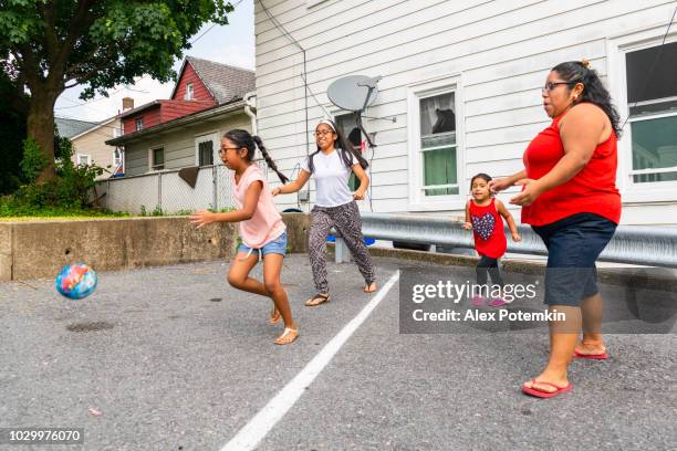 de grote gelukkige latino, mexicaans-amerikaanse familie - de moeder-, lichaam-positieve vrolijke vrouw, en de kinderen, meisjes van verschillende leeftijden - spelen met een bal buiten - hot big women stockfoto's en -beelden