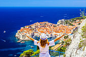 Summer holiday in Croatia- beautiful young female looks at old cityDubrovnik from aerial view.