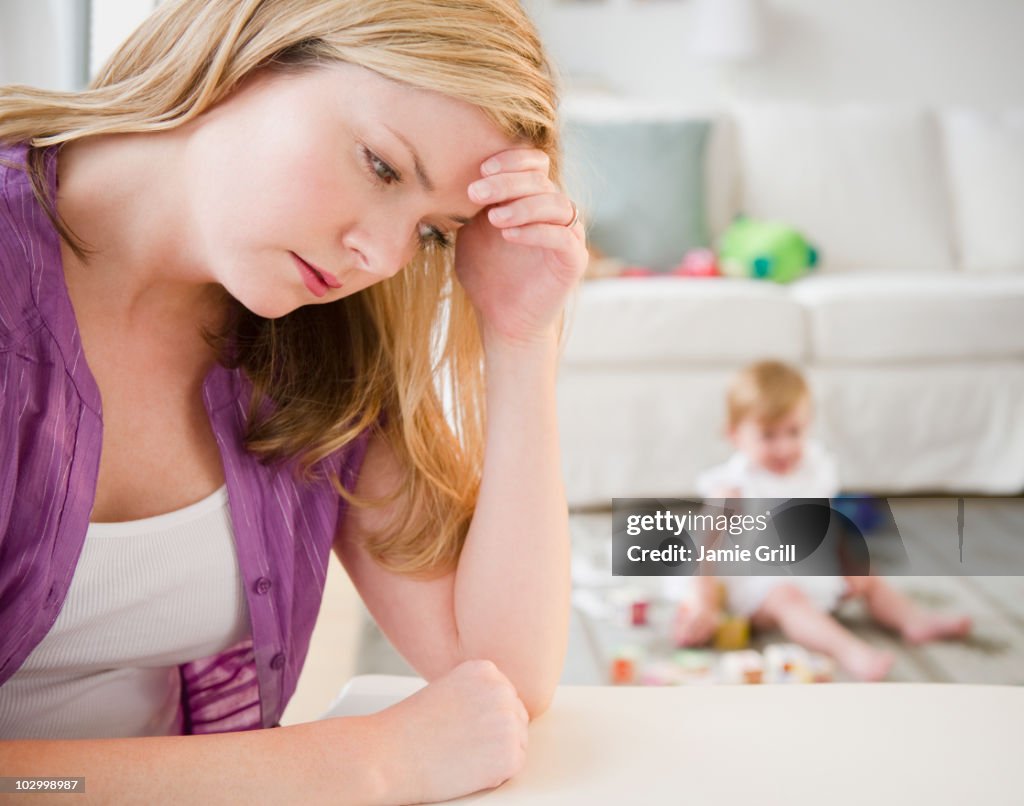 Mother with head in hands, baby in background