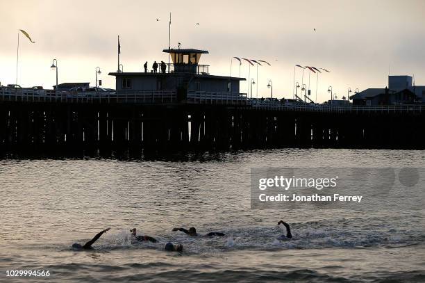 Athletes swim pas the wharf during the Pro Men's Division of the Ironman 70.3 Santa Cruz on September 9, 2018 in Santa Cruz, California.
