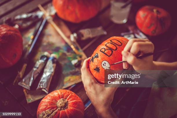 young girl painting on pumpkin in halloween - carving craft activity stock pictures, royalty-free photos & images